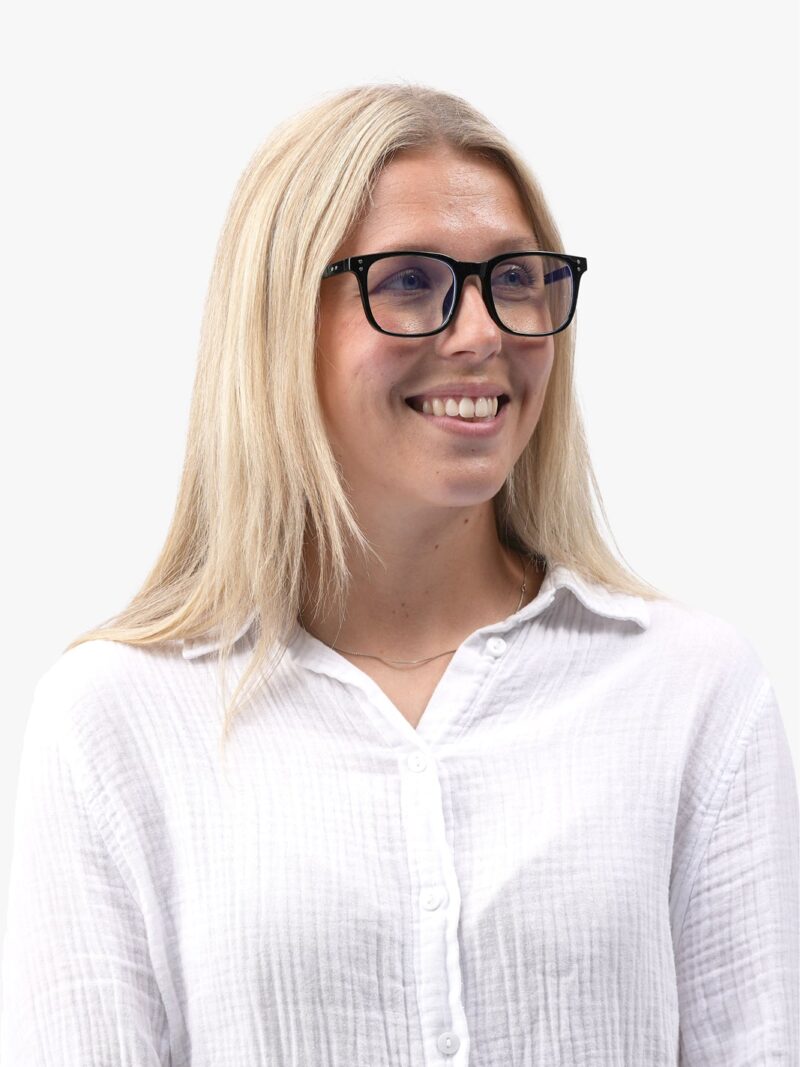 Lächelnde blonde Frau mit schwarzer Brille und weißem Hemd, Porträt vor hellem neutralem Hintergrund