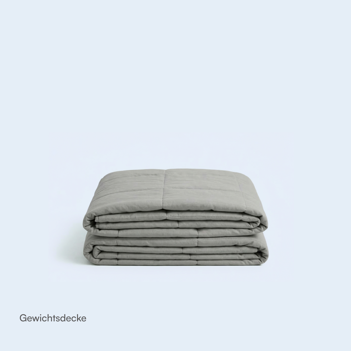 Gefaltete graue Gewichtsdecke mit Steppnähten auf hellem Hintergrund