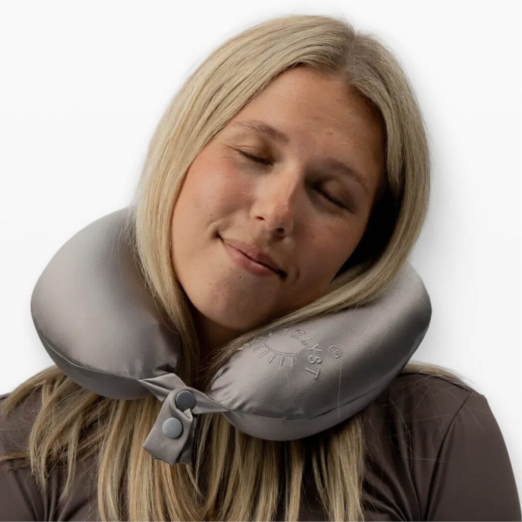 Frau entspannt mit silbergrauem U-förmigem Reisekissen mit Druckknopfverschluss